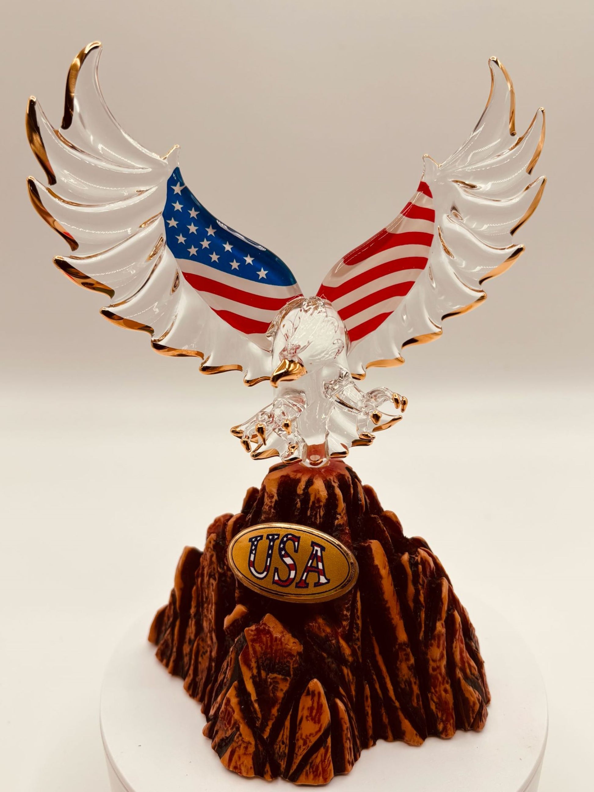 Handcrafted glass eagle with USA flag wings and gold accents standing on rocky base marked US 