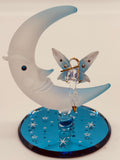 Handcrafted glass fairy beside a frosted moon on a beveled blue mirror base with crystal and gold accents
