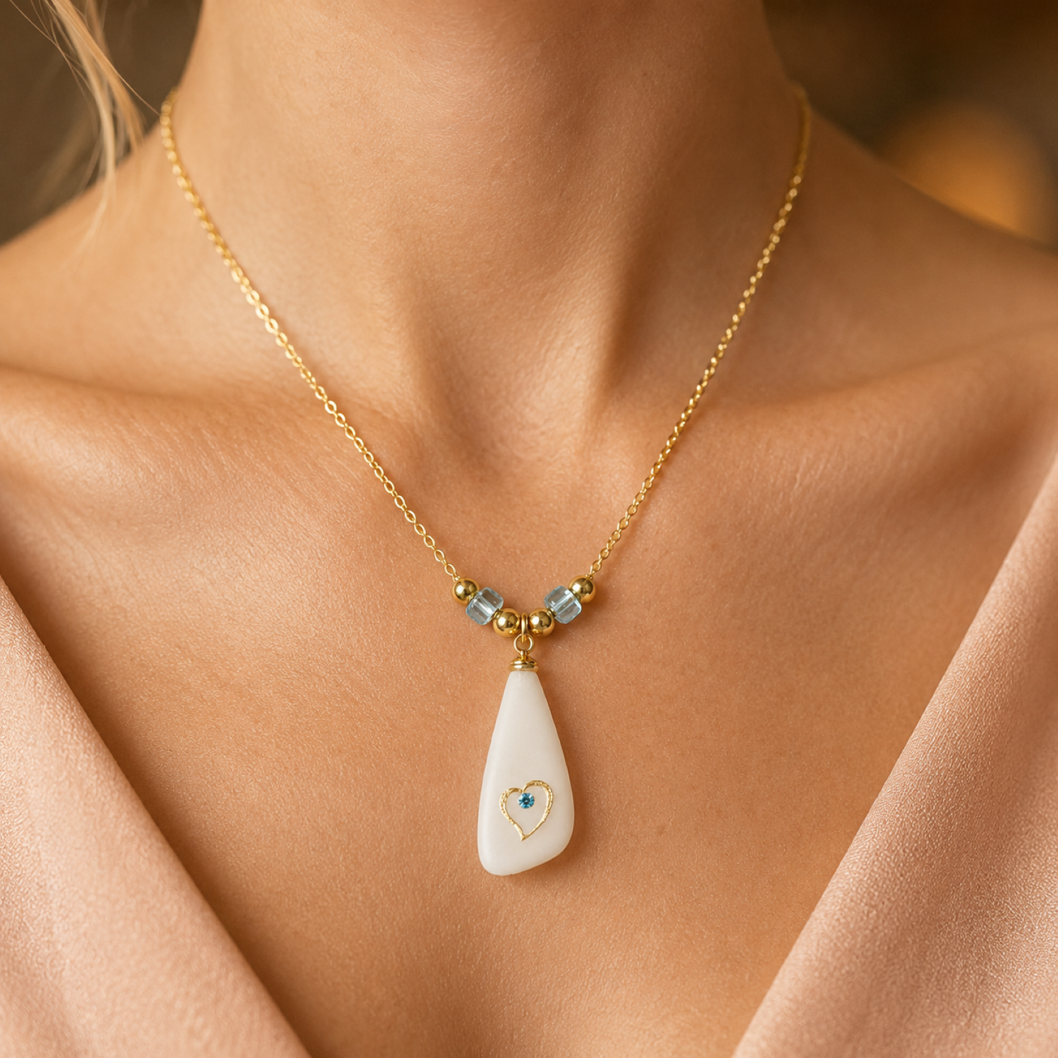 Sea glass heart pendant necklace with frosted white glass-style pendant, gold heart detail, blue crystal accent, blue glass beads, and an 18-inch gold-plated chain.