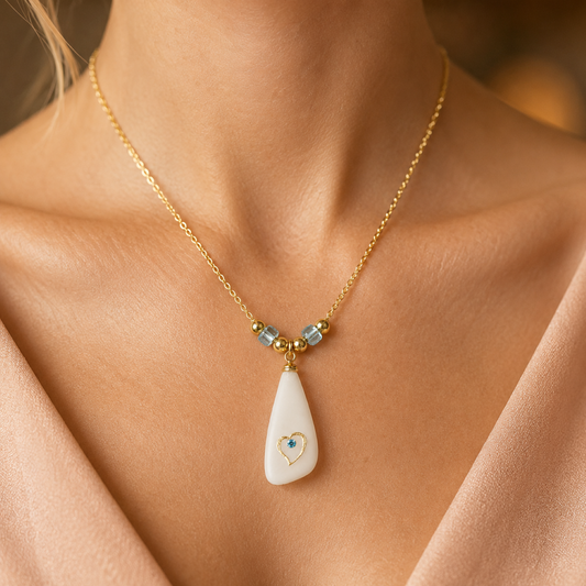 Sea glass heart pendant necklace with frosted white glass-style pendant, gold heart detail, blue crystal accent, blue glass beads, and an 18-inch gold-plated chain.