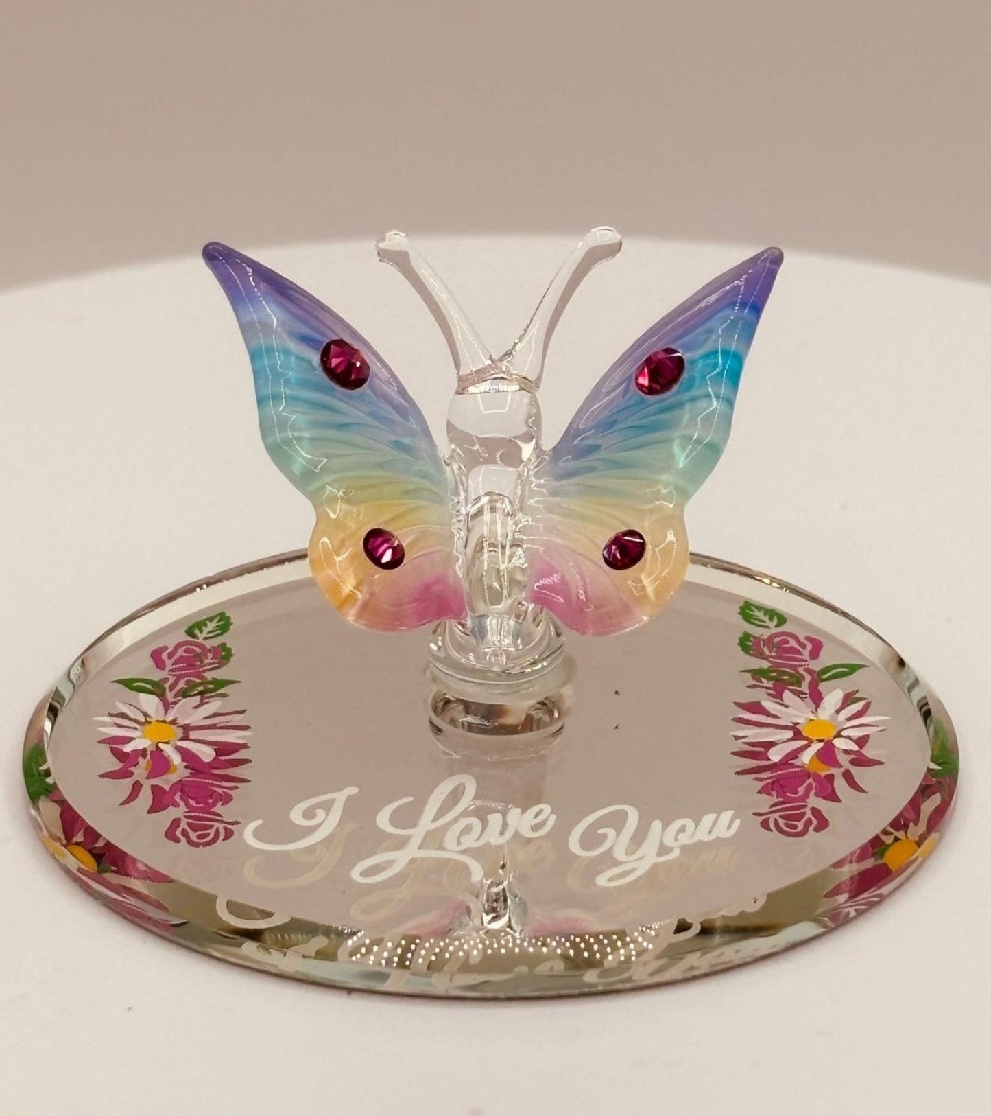 Handcrafted glass butterfly figurine with rainbow coloring on floral mirror base engraved with I Love You