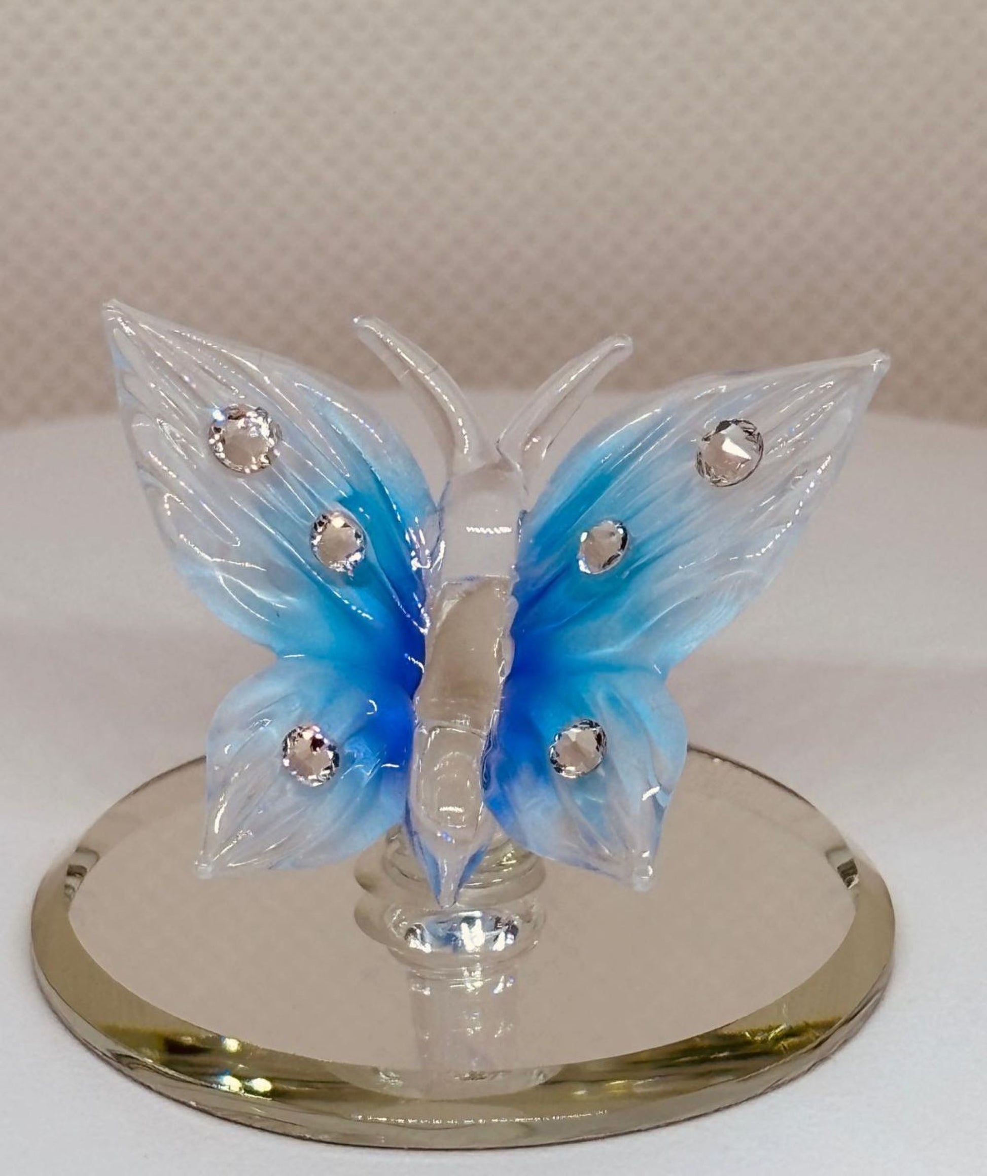 Handcrafted blue glass butterfly figurine on a beveled mirror base