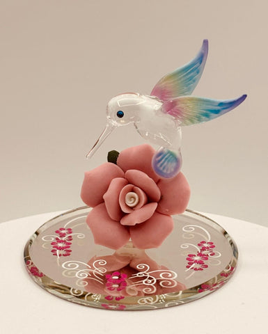 Handcrafted glass hummingbird figurine perched on pink rose with crystal accents on mirror base