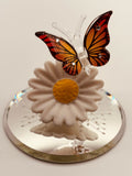 Handcrafted glass butterfly perched on a daisy with crystal accents on a beveled mirror base