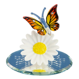 Handcrafted glass butterfly perched on a daisy with crystal accents on a beveled mirror base