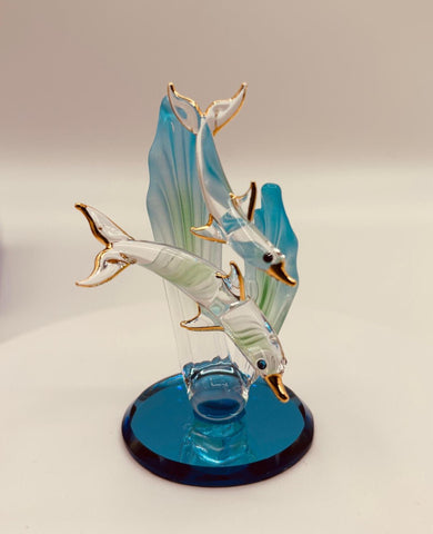 Handcrafted glass dolphin and baby swimming among sea grass on a blue beveled mirror base with crystal and 22Kt gold accents