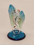 Handcrafted glass sea horse figurine among sea grass on a blue beveled mirror base with crystal and gold accents