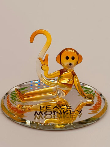 Handcrafted yellow glass monkey figurine with crystal accents on a beveled embossed mirror base featuring Peace Monkey message