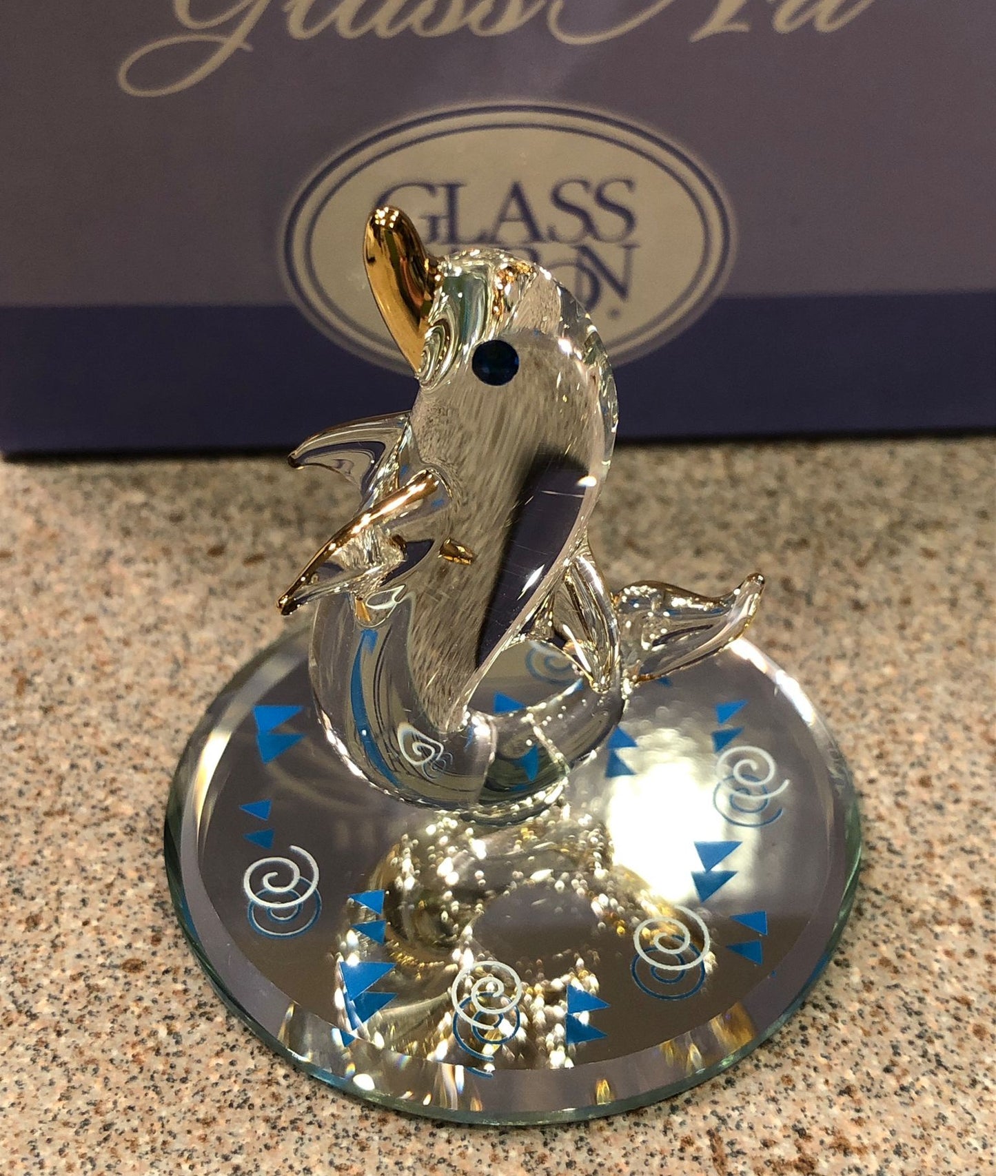 Handcrafted glass dolphin figurine with gold accents, blue crystal eye, and hand-beveled glass mirror base.