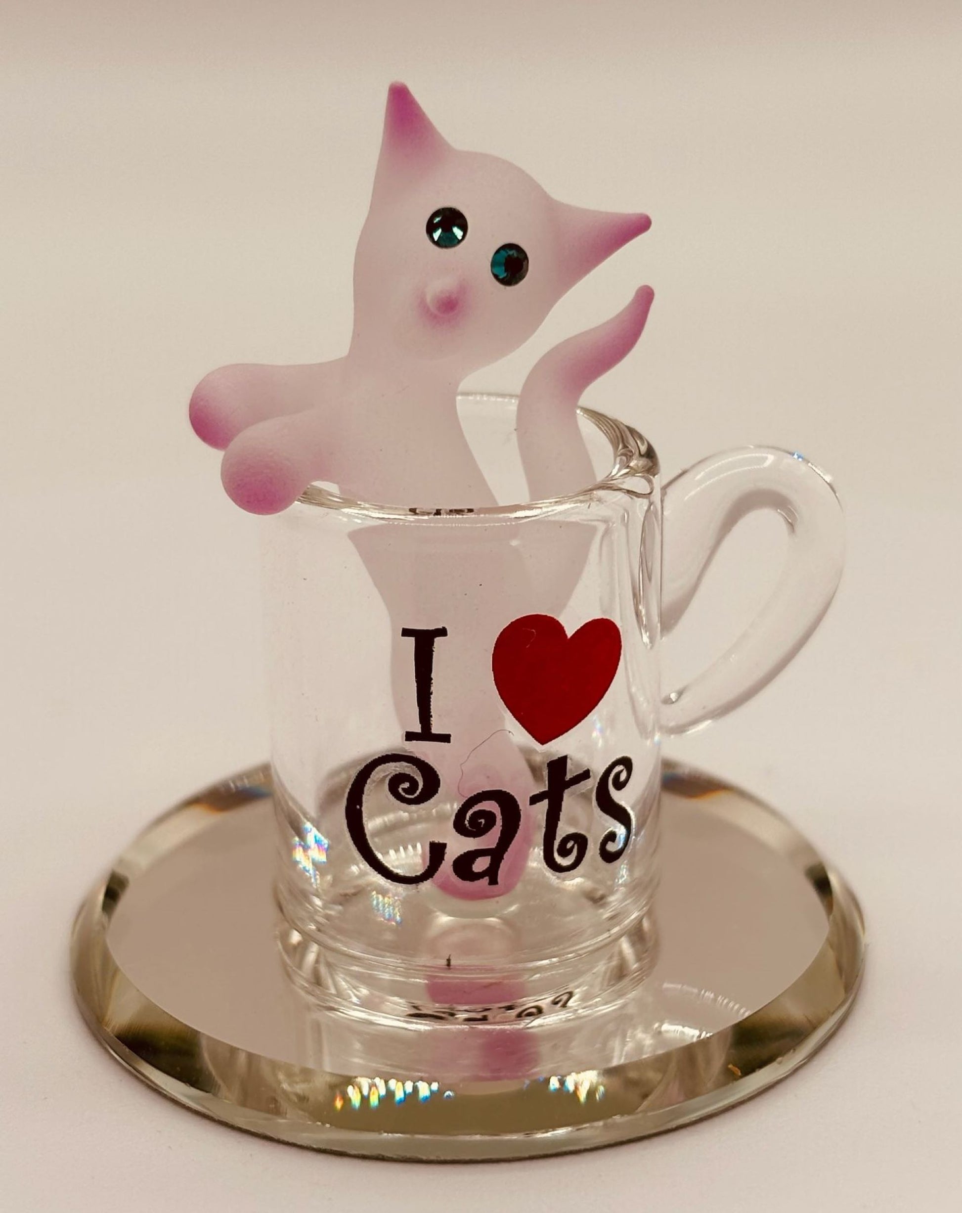 Handcrafted white and pink cat figurine sitting in a glass coffee cup on beveled mirror base with “I ♥ Cats” sentiment