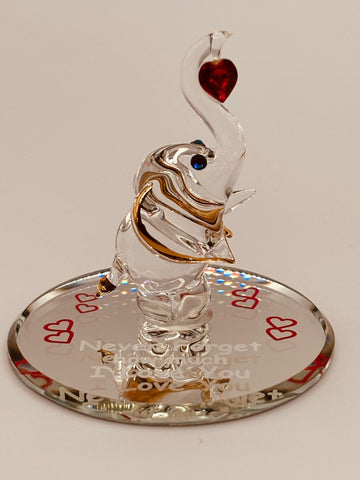 Handcrafted glass elephant holding a red crystal heart on beveled mirror base with “Never Forget how much I Love You” message