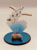 Handcrafted sea turtle with blue coral glass figurine accented with crystals and 22Kt gold on a blue mirror base. A peaceful coastal décor collectible for ocean lovers.