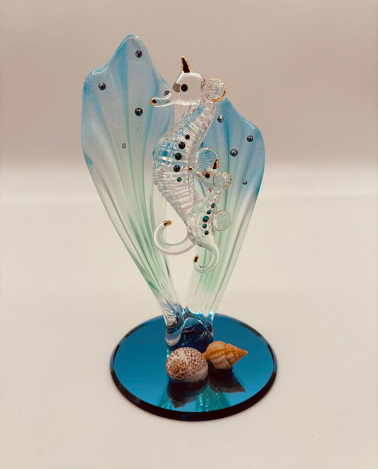 Handcrafted glass sea horses swimming among blue sea grass on a beveled blue mirror base with crystal and gold accents