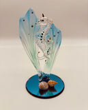 Handcrafted glass sea horses swimming among blue sea grass on a beveled blue mirror base with crystal and gold accents