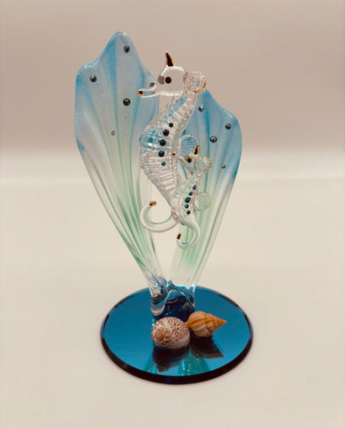 Handcrafted glass sea horses swimming among blue sea grass on a beveled blue mirror base with crystal and gold accents