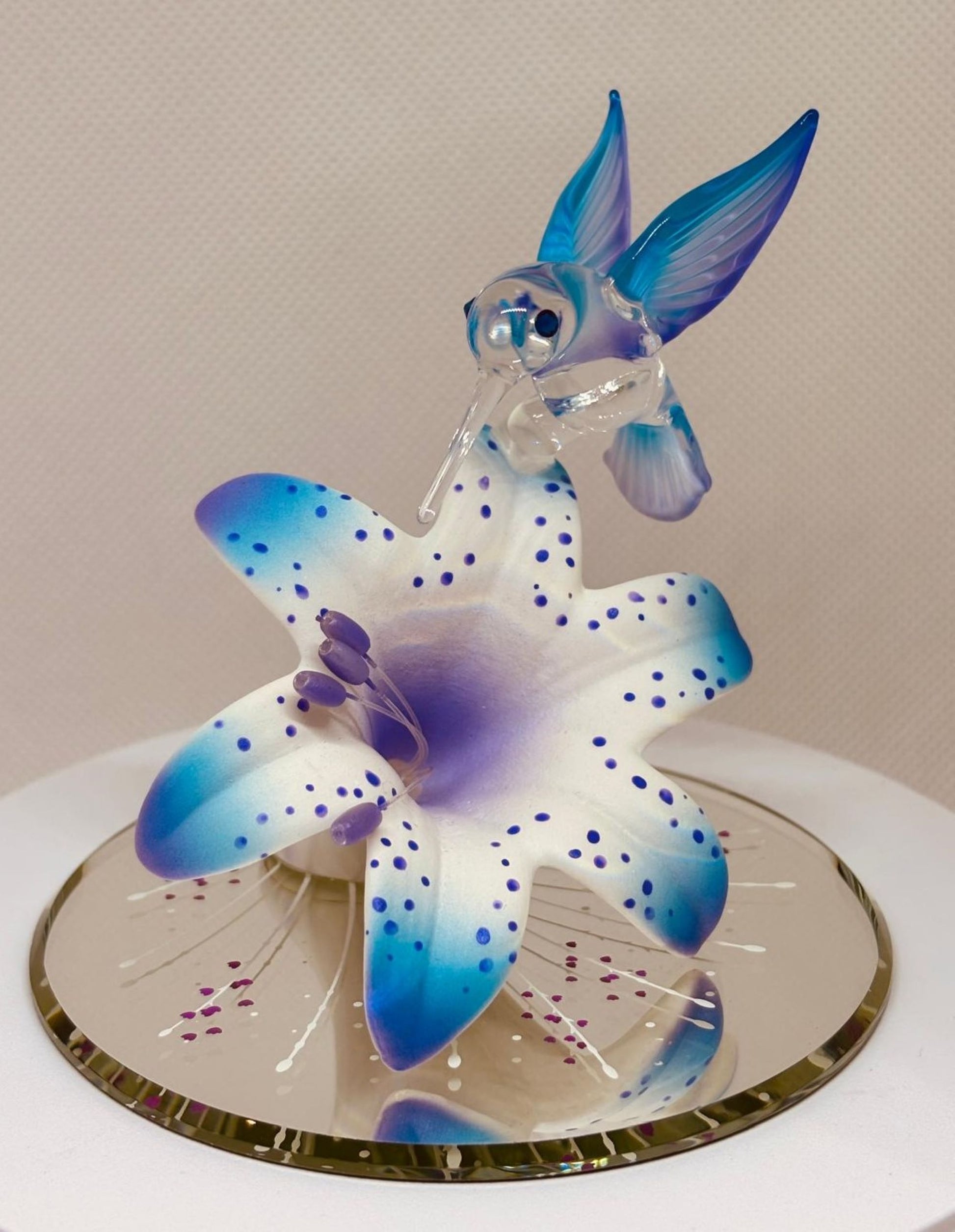 Handcrafted glass hummingbird perched on blue and white lily with crystal accents