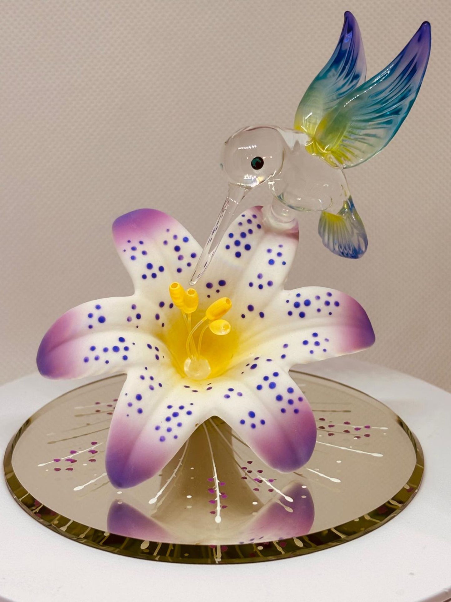 Handcrafted glass hummingbird perched on lavender lily with crystal accents
