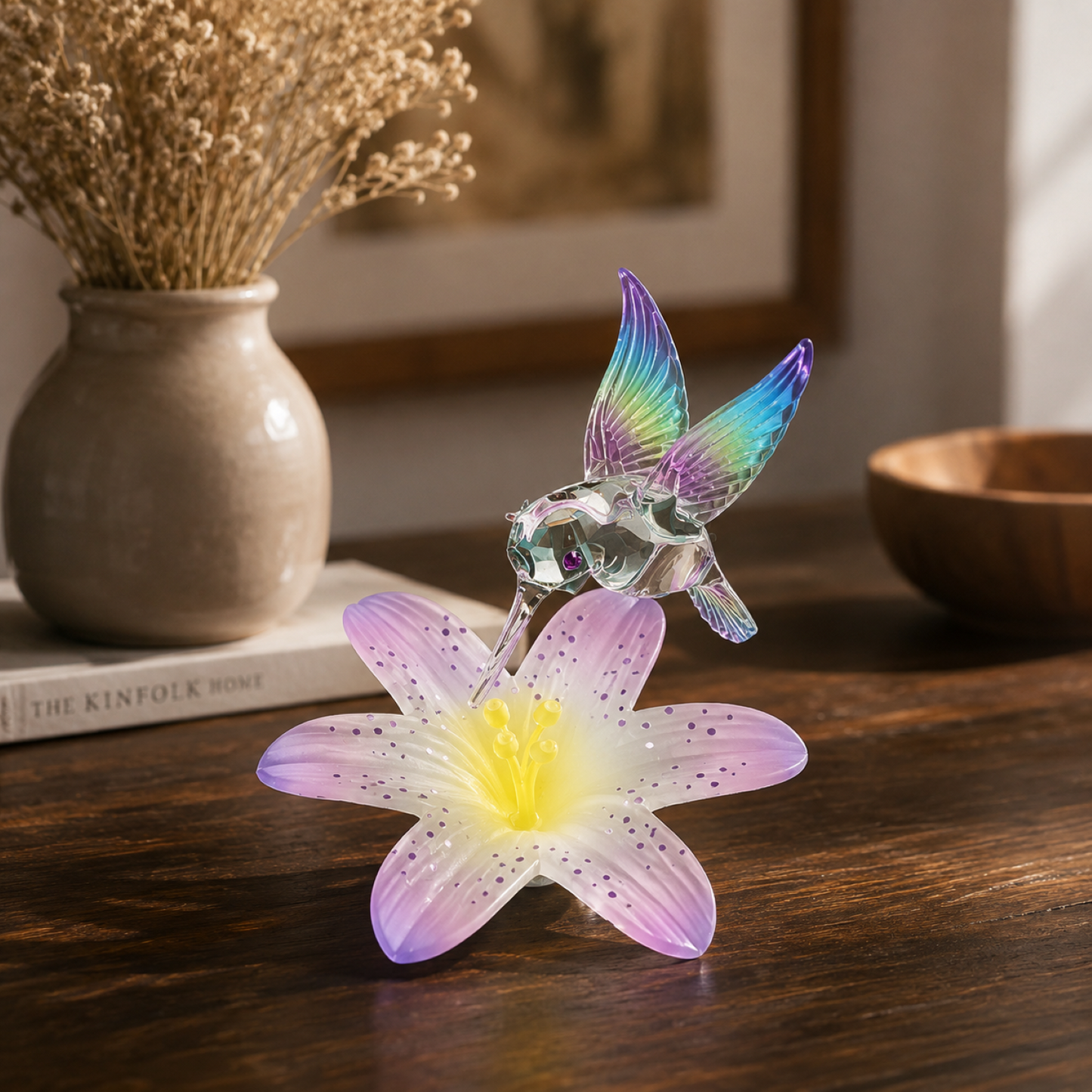 Handcrafted hummingbird glass figurine hovering above pastel flower decorative collectible display.