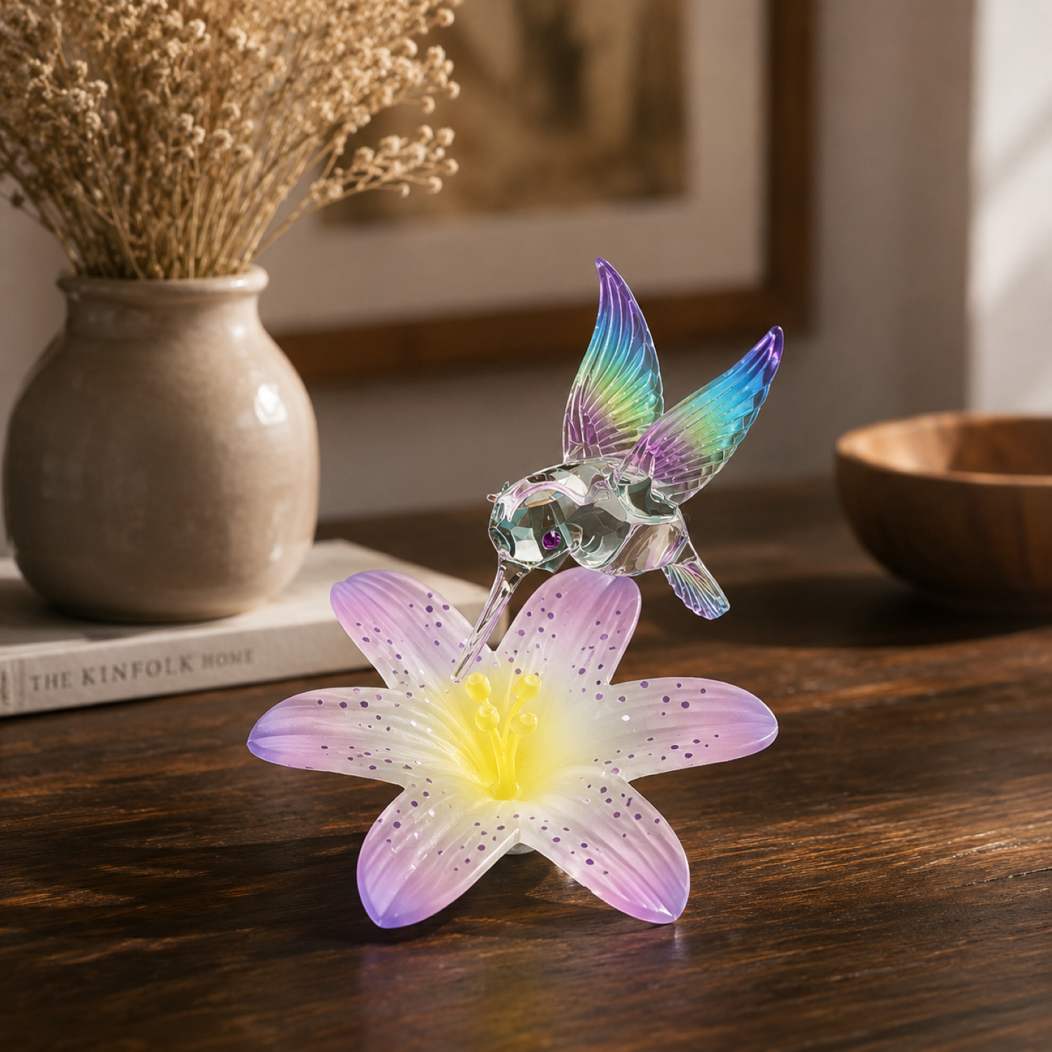 Handcrafted hummingbird glass figurine hovering above pastel flower decorative collectible display.