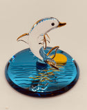 Handcrafted glass dolphin figurine riding waves on a sunset mirror base with crystal and 22Kt gold accents