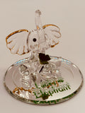 Handcrafted glass lucky elephant figurine with green crystal eyes and clover accents on beveled mirror base